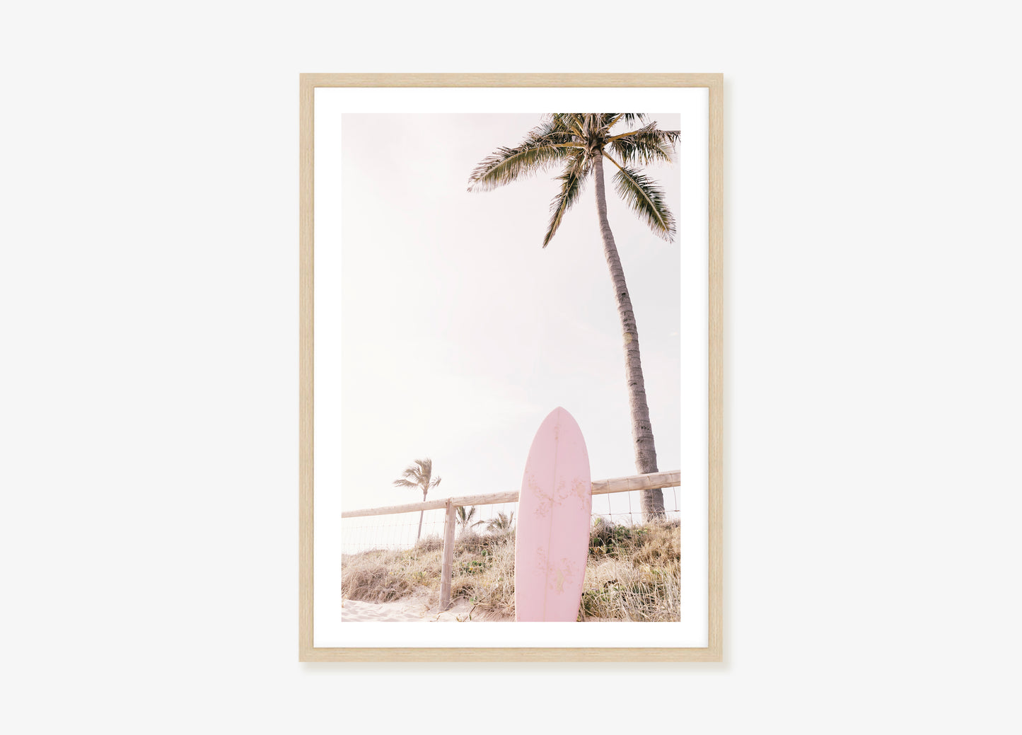 a pink surfboard sitting in front of a palm tree